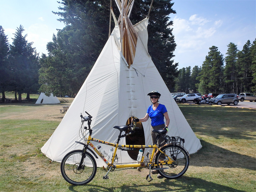 Terry and the Bee are standing in front of a Teepee.